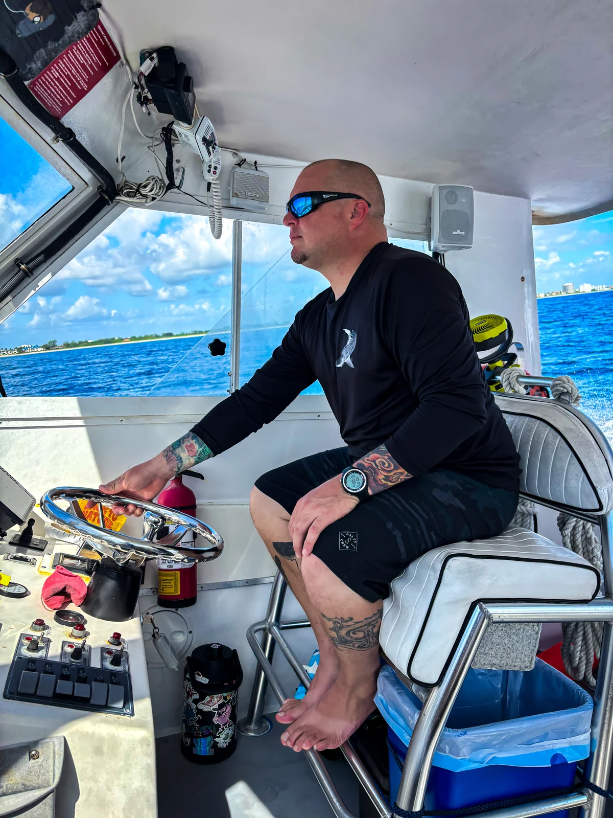 Adam Foglia seated at the helm of the Mama Tee with the ocean behind him