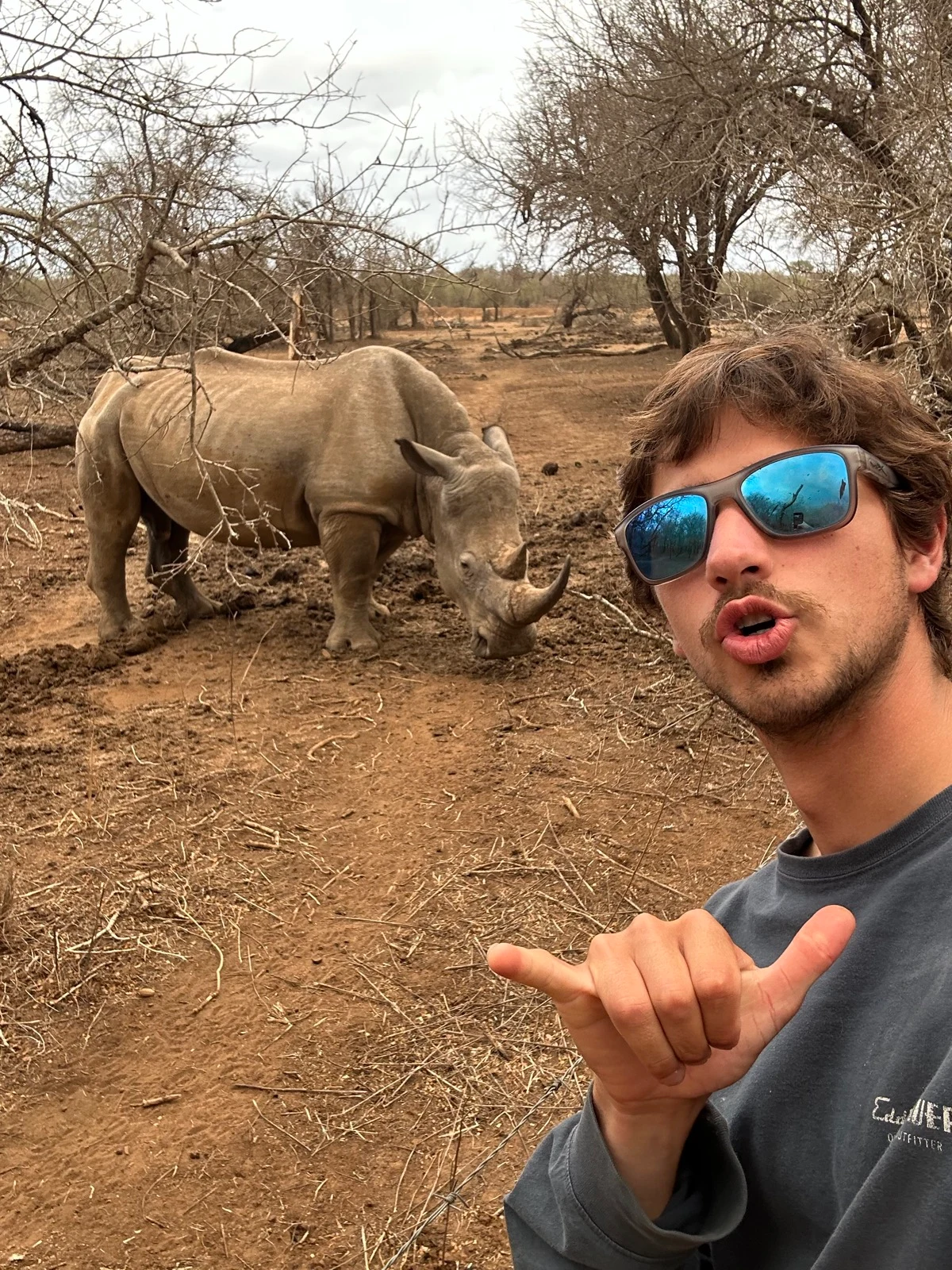 Miles Merhib wearing sunglasses with a rhinoceros in the background