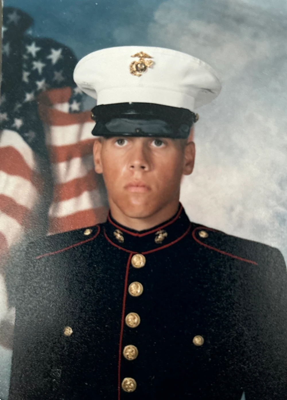Nic Lombardo in United States Marine Corps dress uniform beside an American flag